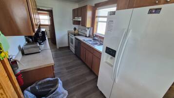 A kitchen with wooden cabinets, a white refrigerator, a stove, and a dishwasher.