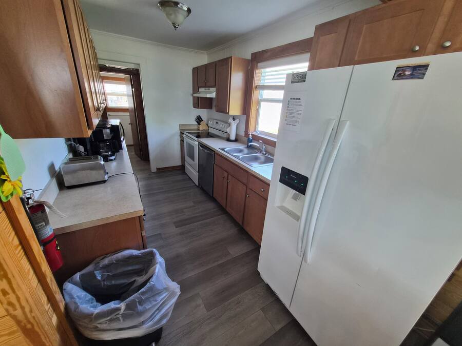 A kitchen with wooden cabinets, a white refrigerator, a stove, and a dishwasher.