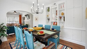 A dining area with a dark wooden table, blue chairs, and a chandelier. - Kayak from your backyard (Bradenton)