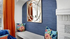 A room with a white bench, colorful pillows, a blue textured wall, and a geometric mirror. - Kayak from your backyard (Bradenton)