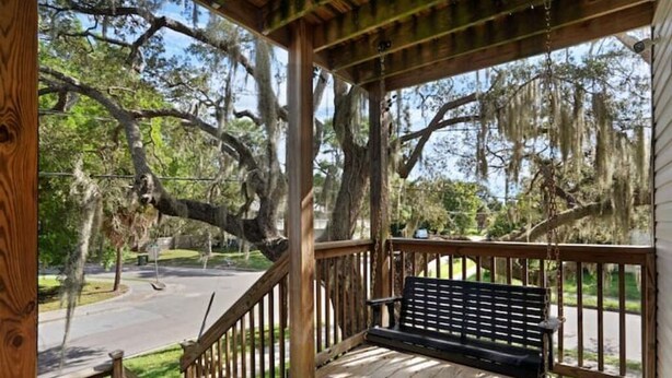 A wooden porch with a bench, overlooking a street with trees and a clear sky. - Kayak from your backyard (Bradenton)