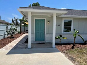 Welcome to a charming home with a light blue door, surrounded by a white fence and a paved driveway.
