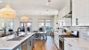 A modern kitchen with white cabinetry, a central island, and pendant lighting. - The Barracuda - Cape San Blas (Port Saint Joe)