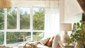 A cozy room with a white sofa, a round rug, and a wooden table with a lamp. - Country House North of Spain (Lamadrid)