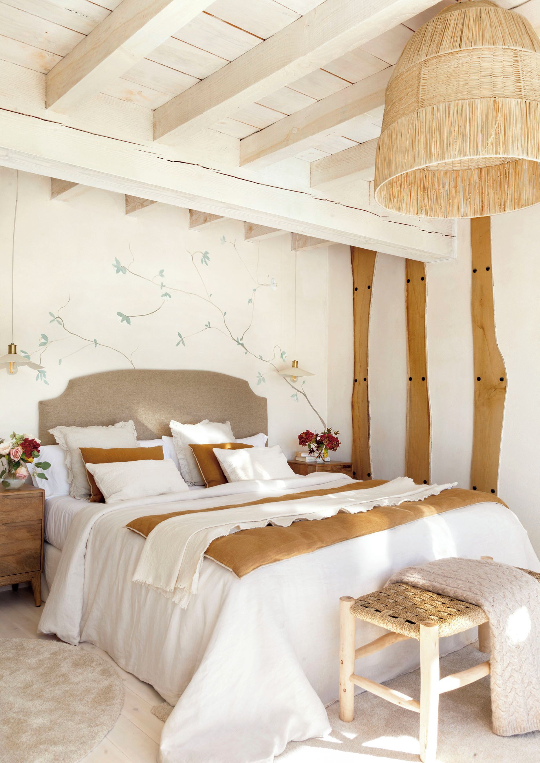 Quarto com uma cama grande, um banco de madeira e um lustre.