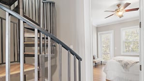 A staircase with metal railings and wooden steps leading to a bedroom with a bed and a ceiling fan. - 30A, 300ft to beach, pool, pingpong, foosball, GulfPlace, ocean views! (Santa Rosa Beach)