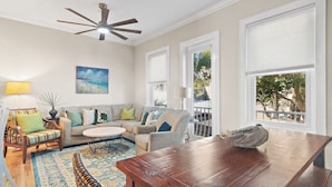 A living room with a sofa, armchairs, a coffee table, and a wooden dining table. There are two windows with blinds, a ceiling fan, and a painting on the wall. - 30A, 300ft to beach, pool, pingpong, foosball, GulfPlace, ocean views! (Santa Rosa Beach)