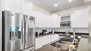 A modern kitchen with stainless steel appliances, white cabinets, a granite countertop, and a built-in microwave. - 30A, 300ft to beach, pool, pingpong, foosball, GulfPlace, ocean views! (Santa Rosa Beach)