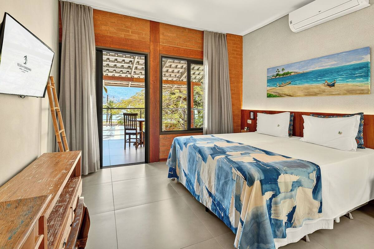 A hotel room with a bed, a desk, and a view of the outdoors.