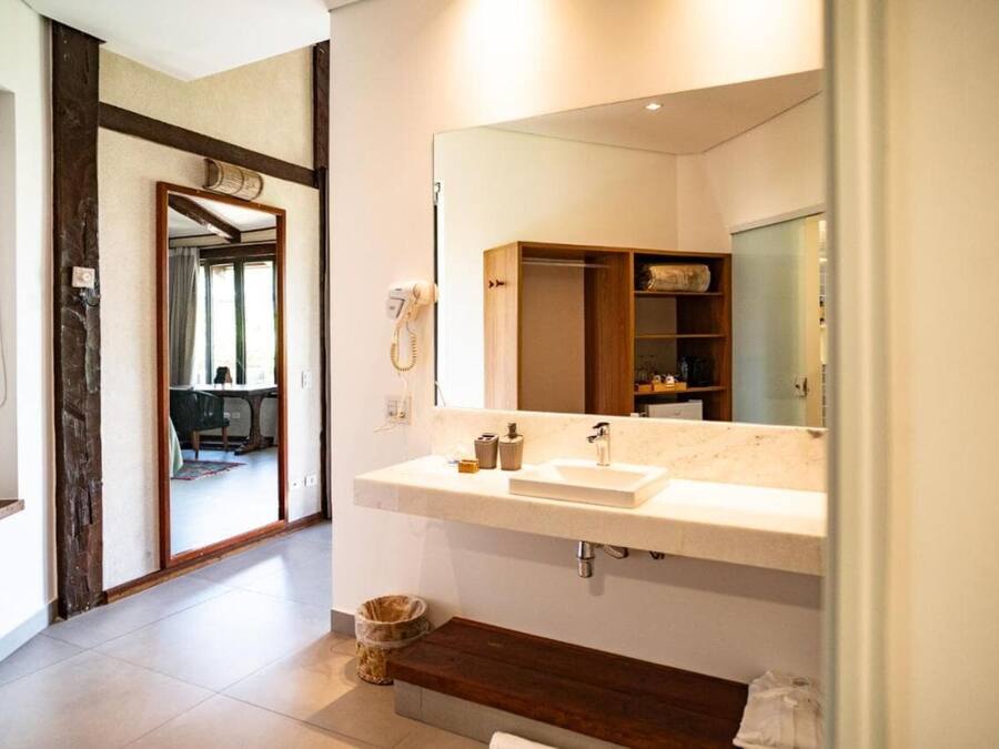 Un baño moderno con un espejo grande, un lavabo blanco y estanterías de madera.