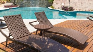 Zona de piscina con dos sillones de mimbre y una mesita.