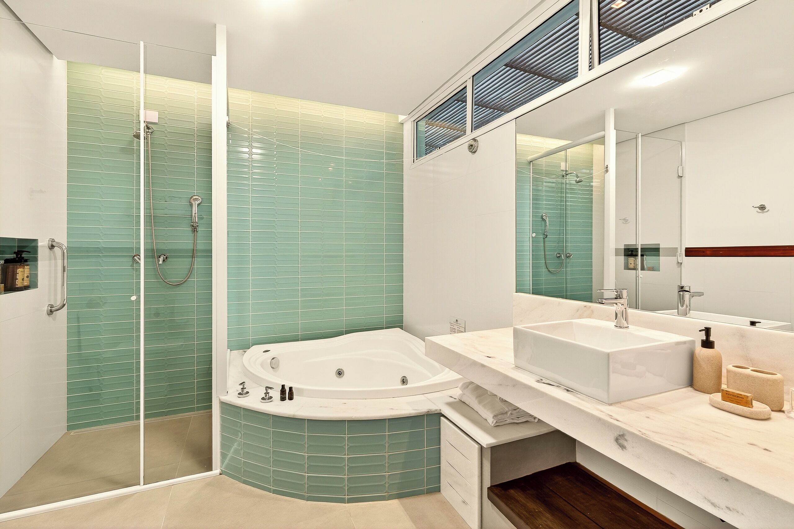 A modern bathroom with a glass-enclosed shower, a freestanding bathtub, and a vanity with a large mirror.