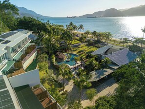 A resort with a pool, palm trees, and a view of the sea.