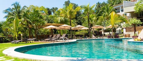 Una piscina al aire libre, sombrillas, sillones reclinables de piscina