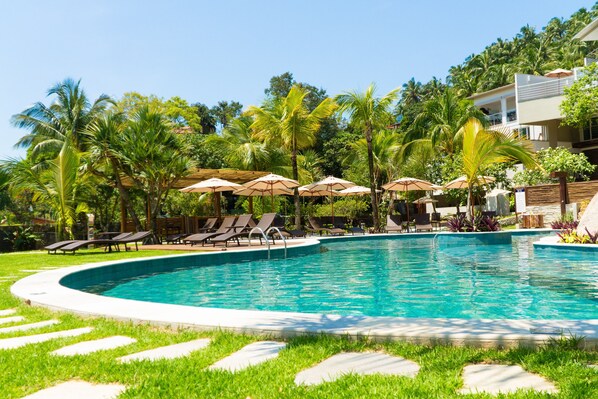 Alberca al aire libre, sombrillas en la alberca y camastros 