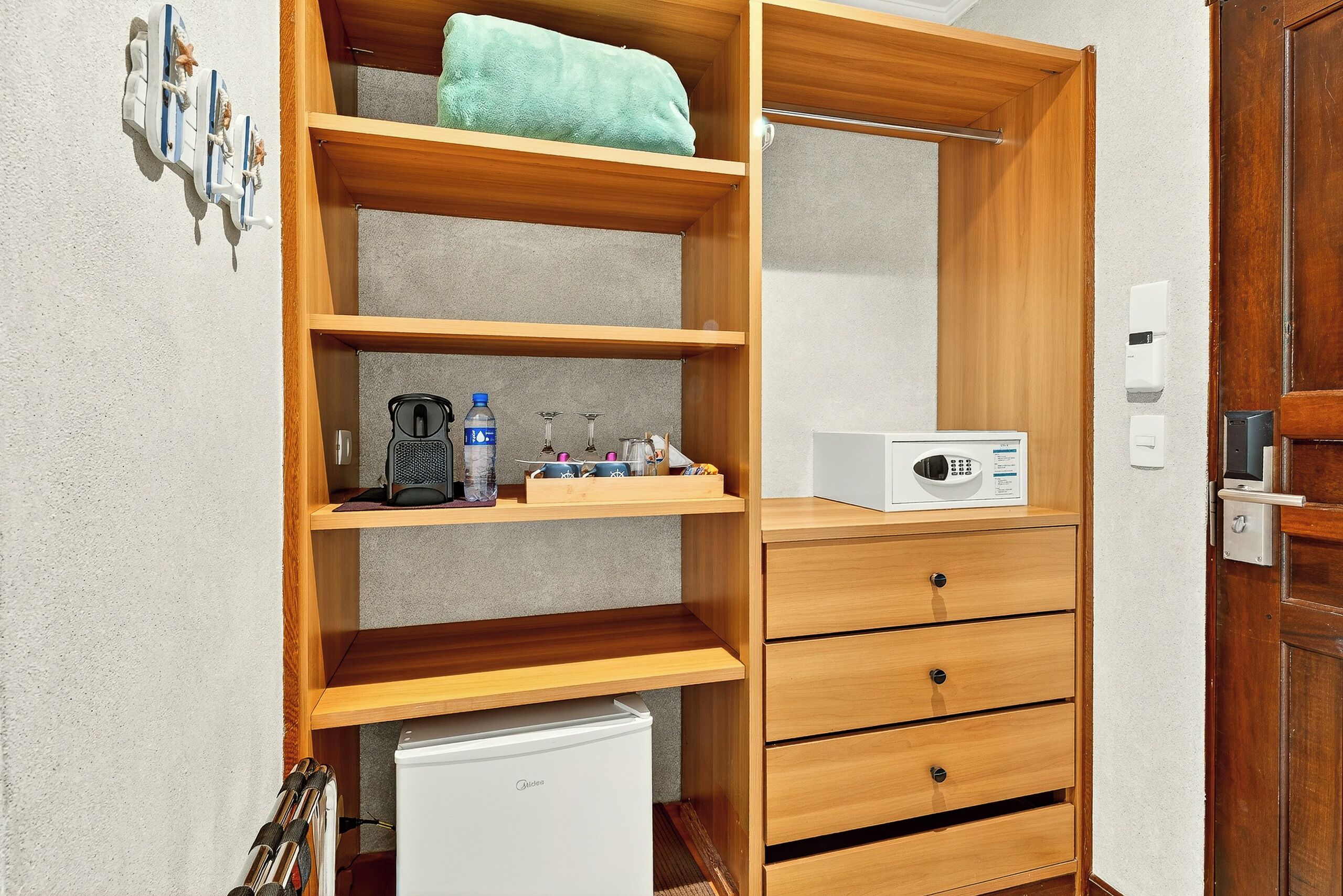 A compact room with a wooden wardrobe, a microwave, and a small refrigerator.