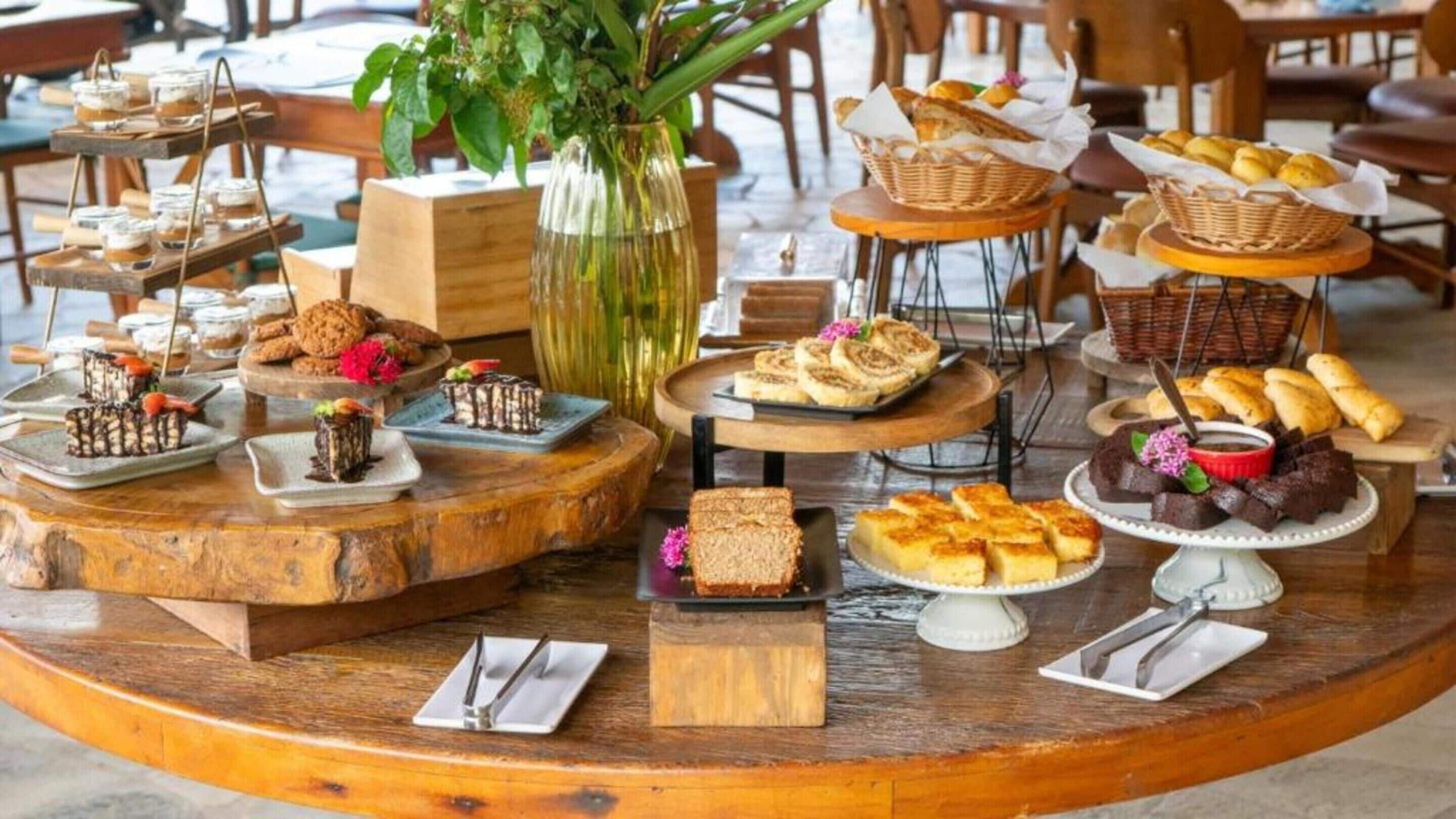 Una variedad de postres y pasteles expuestos sobre una mesa de madera en un café.