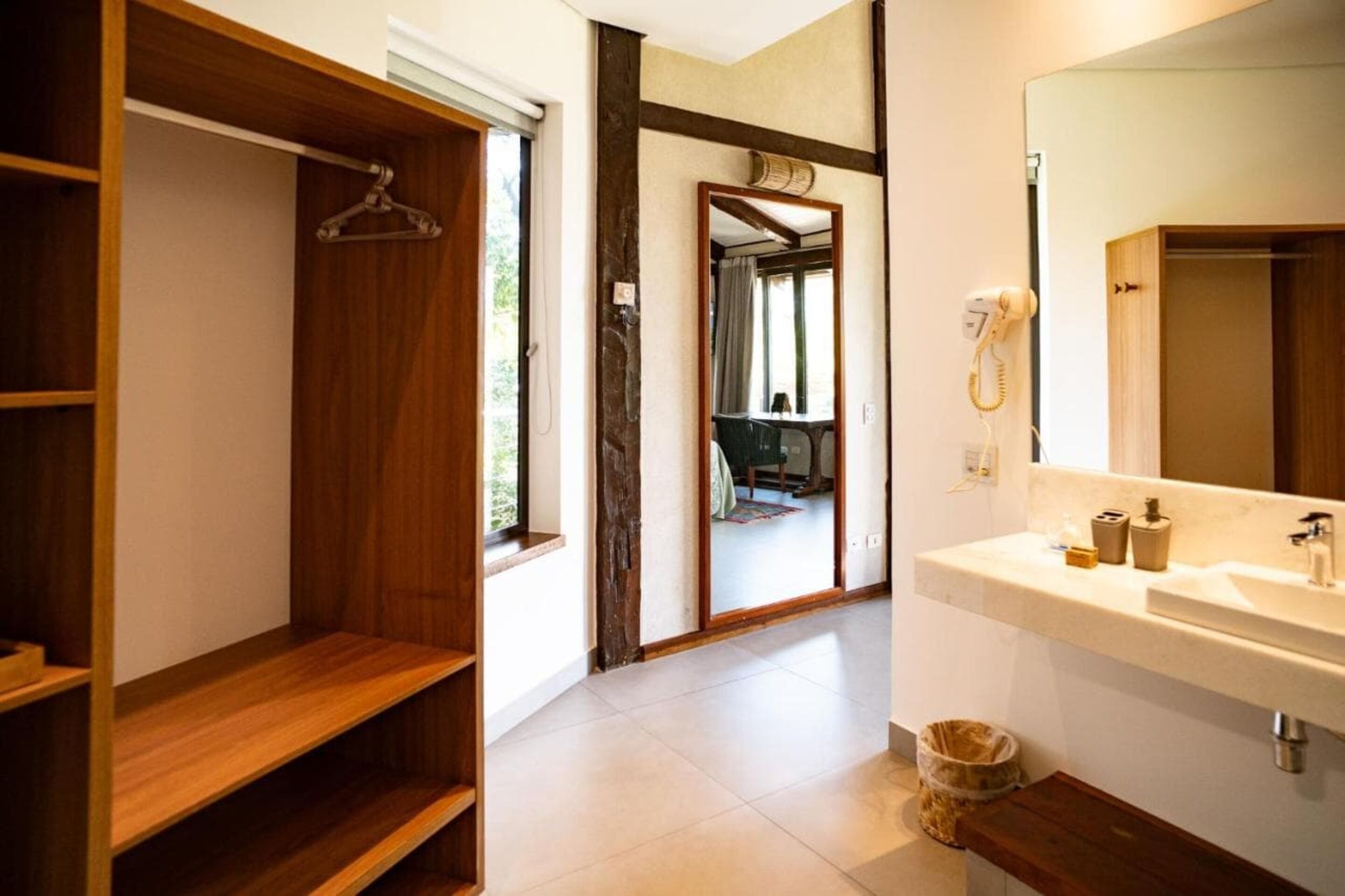 Un baño con tocador de madera, un espejo, un lavamanos y un perchero para toallas.