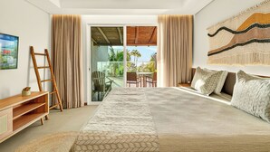 Un dormitorio con cama, una escalera de madera, un mueble para televisión y vistas al exterior.