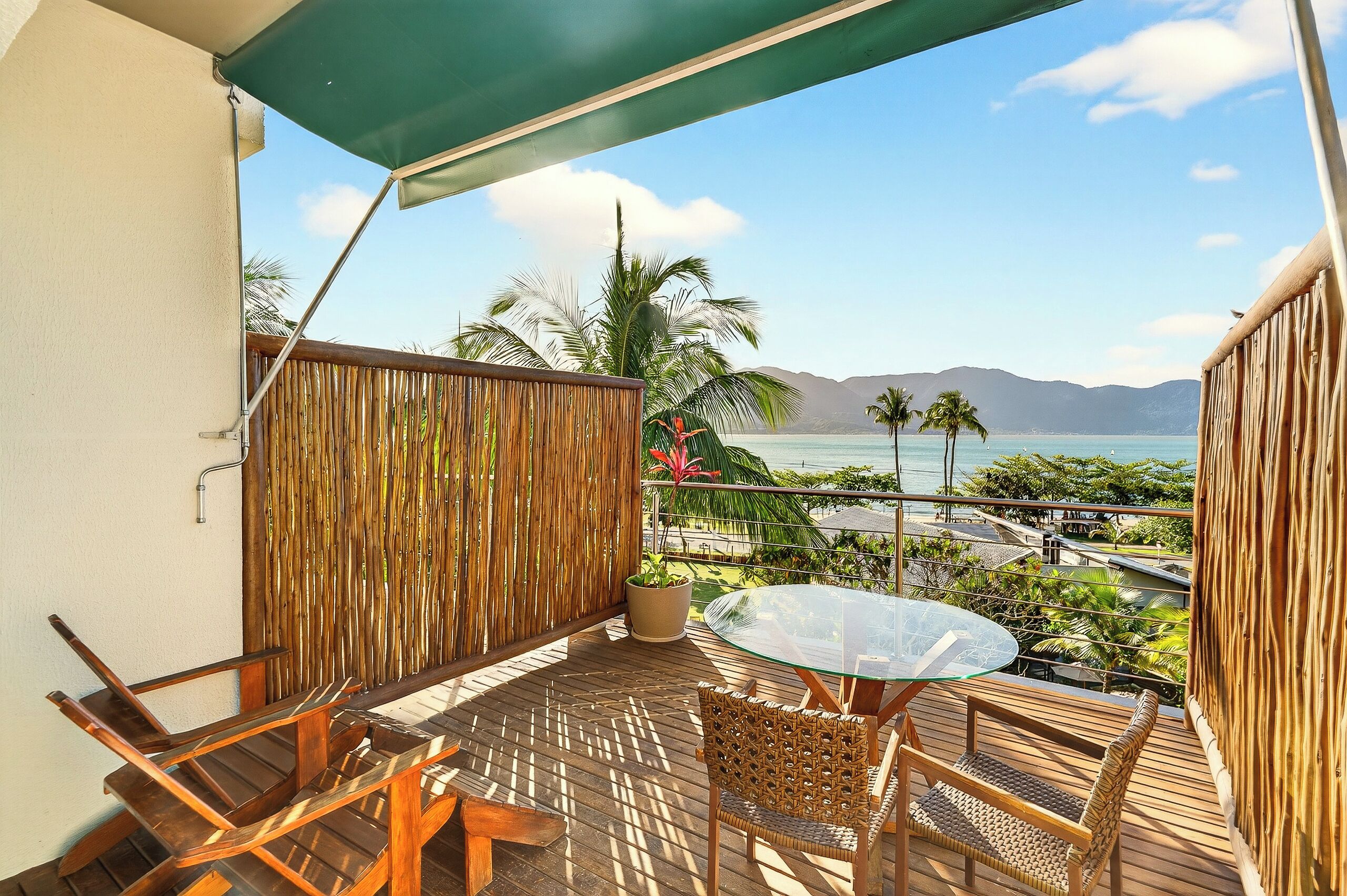 A balcony with a table and chairs, a view of the ocean, and a wooden fence.