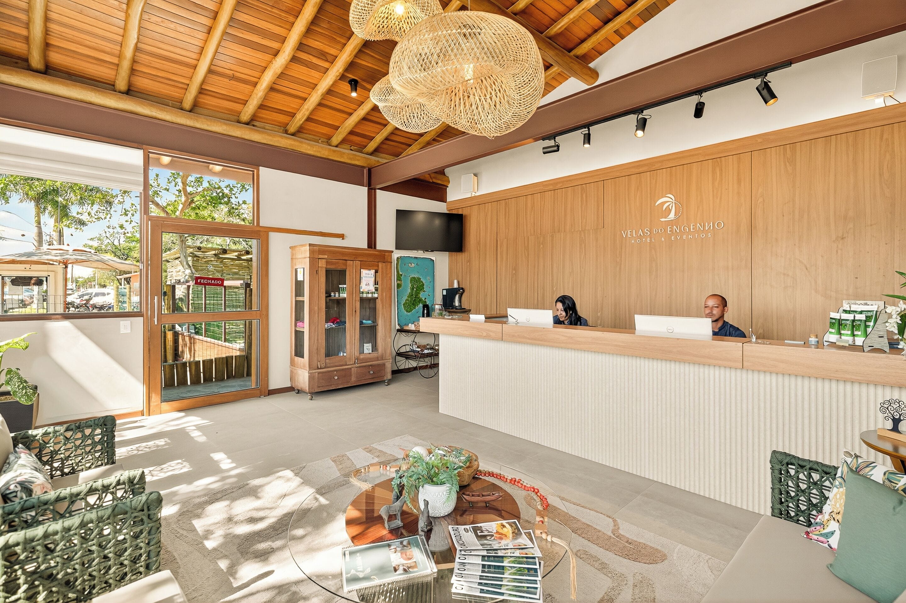 A reception area with a wooden reception desk, a large window, and a seating area with wicker furniture.