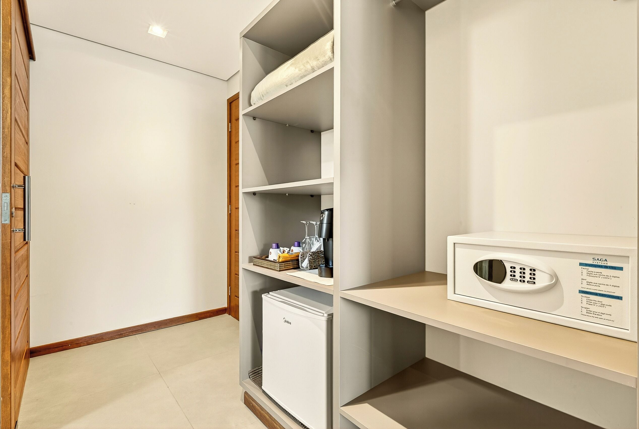Camera compatta e moderna con spazio contenitori integrato, un mini-frigorifero e un forno a microonde su un ripiano.