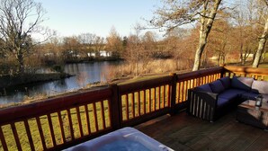 Un jacuzzi en una terraza con vista a un lago y árboles.