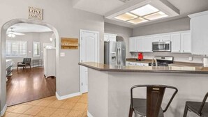 A modern kitchen with white cabinets, a stainless steel refrigerator, and a built-in microwave.