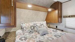 Ein Schlafzimmer mit einem Bett, Holzschränken und einer Deckenleuchte.