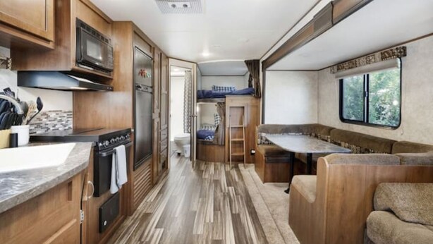 Eine kleine Küchenzeile für Wohnmobile mit Holzschränken, einer Mikrowelle, einem Herd und einem Spülbecken.