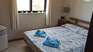 A bedroom with a bed, a heater, a window with curtains, and a bedside table with a lamp. - Marsalforn flat near beach and boulevard (Zebbug)