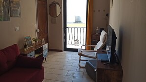 A living room with a red sofa, a wooden cabinet, and a TV on a wooden stand. - Marsalforn flat near beach and boulevard (Zebbug)