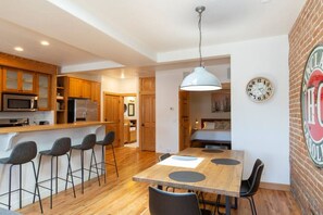 Enjoy meals in the kitchen with a central island and dining area featuring a brick wall and stainless steel appliances.