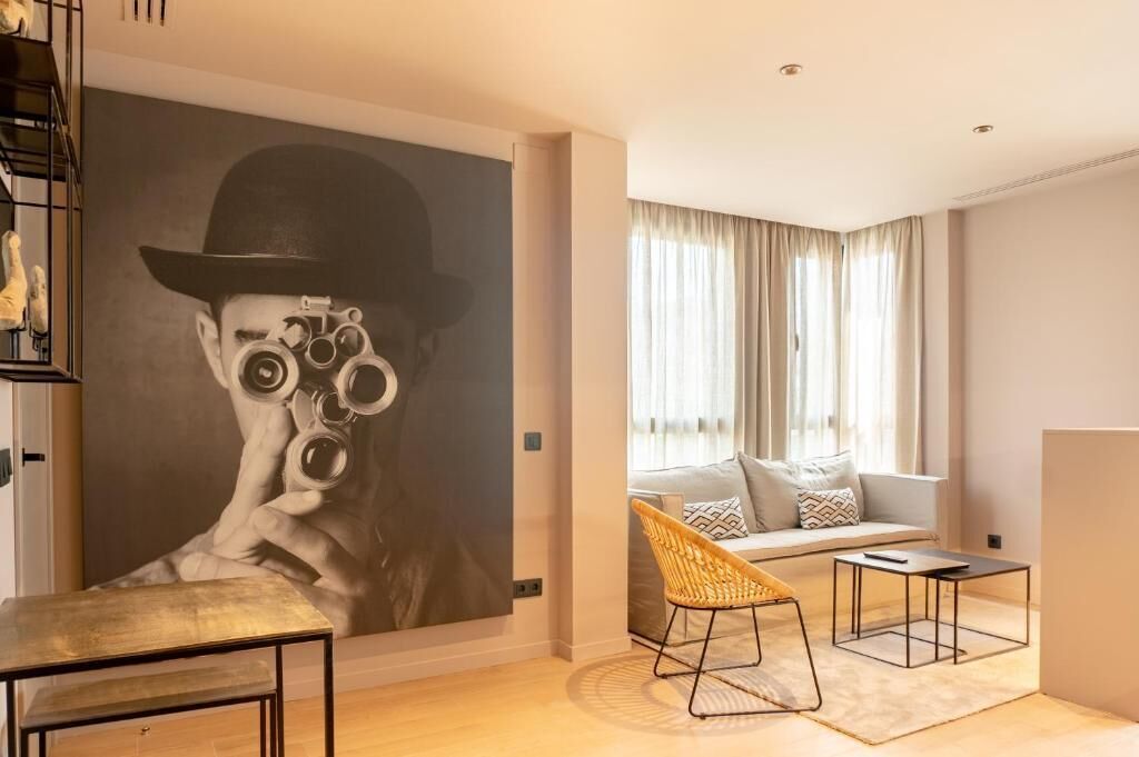 A modern living room with a large abstract painting, a sofa, a wicker chair, and a coffee table.