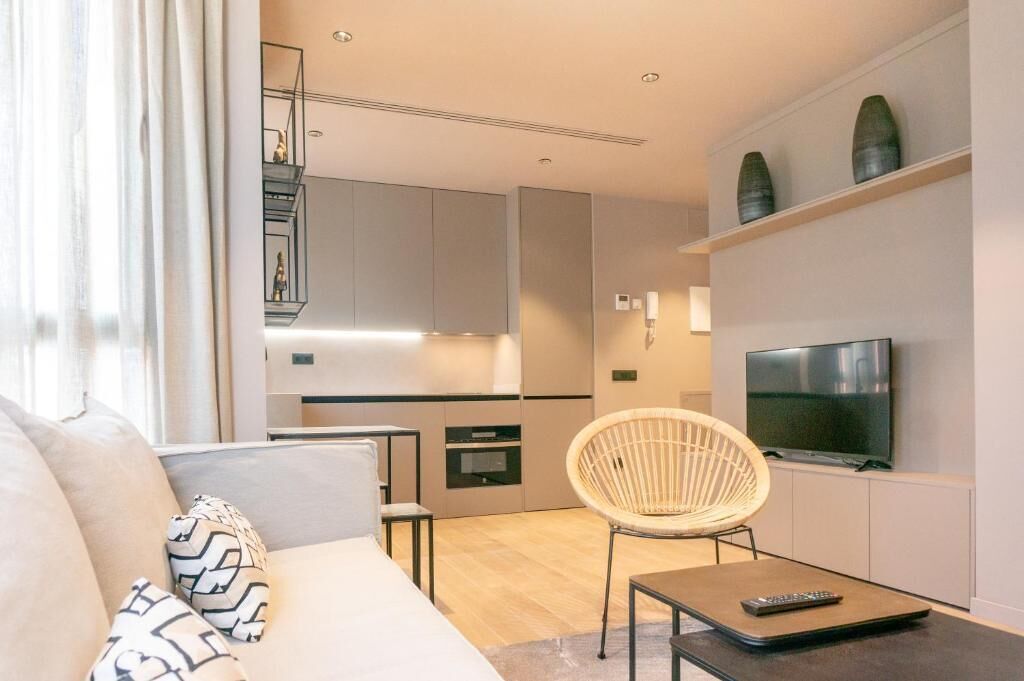 Una sala de estar moderna con un sofá, una silla de mimbre, una mesa de centro y un televisor.