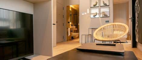 Una sala moderna con un televisor de pantalla plana, una mesa de madera oscura y una silla de mimbre.