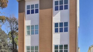 A multi-story building with a modern architectural design, featuring large windows and a combination of white and wooden siding. - Seaside Splendor! Rooftop Views, 3 Minute Walk to Beach (Carolina Beach)