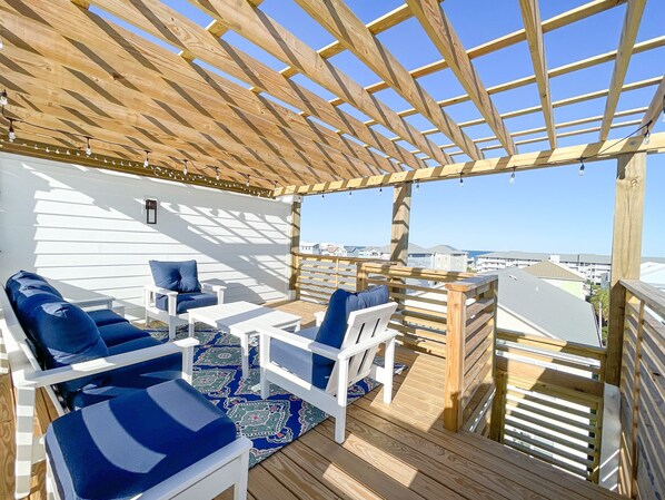 A covered outdoor seating area with wooden furniture and a view of the city.