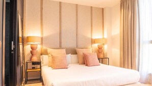 A hotel room with a large bed, two bedside tables with lamps, and a view of the outdoors through a window with curtains. - Valencia Luxury - Sea Port II (Valencia)