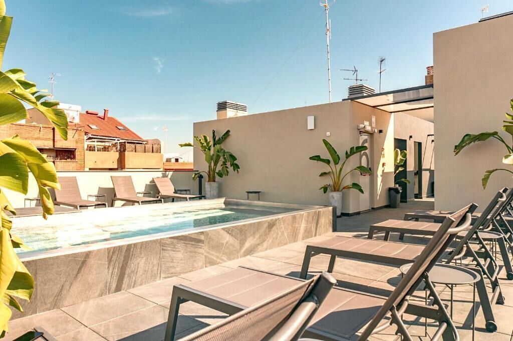 Un espace piscine aménagé sur le toit, avec des chaises longues et des plantes en pot.