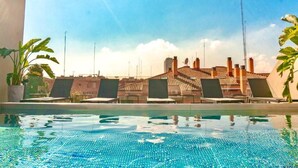 A rooftop pool with lounge chairs and potted plants, overlooking a cityscape with buildings and a clear sky. - Valencia Luxury - Sea Port II (Valencia)