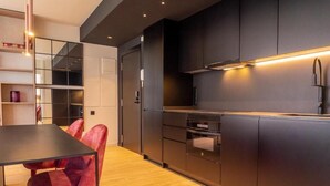 A modern kitchen with dark cabinetry, a wooden countertop, and a built-in oven. - Valencia Luxury - Sea Port II (Valencia)
