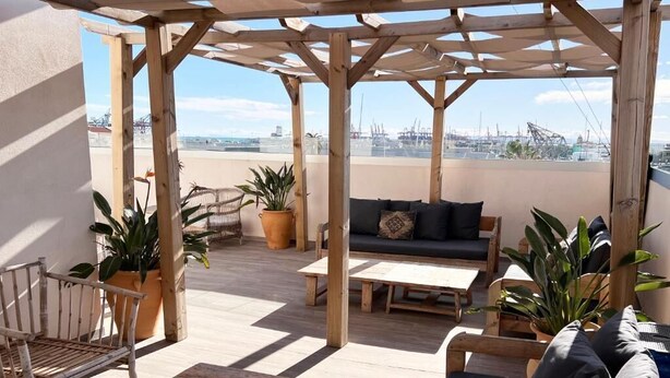 A wooden deck with a sofa, a bench, and potted plants. - Valencia Luxury - Calma Beach Apartments (Valencia)