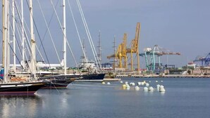 A marina with several sailboats docked, cranes, and industrial structures in the background. - Valencia Luxury - Calma Beach Apartments (Valencia)