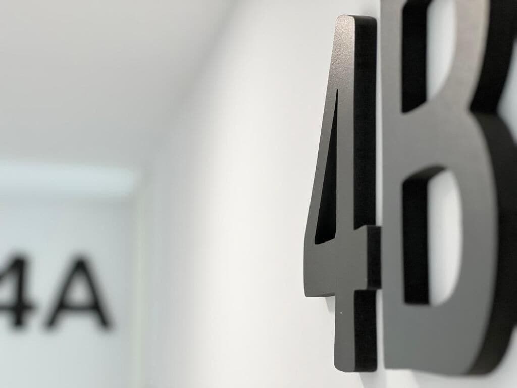 A close-up of a metallic sign with the letters "4B" mounted on a wall.