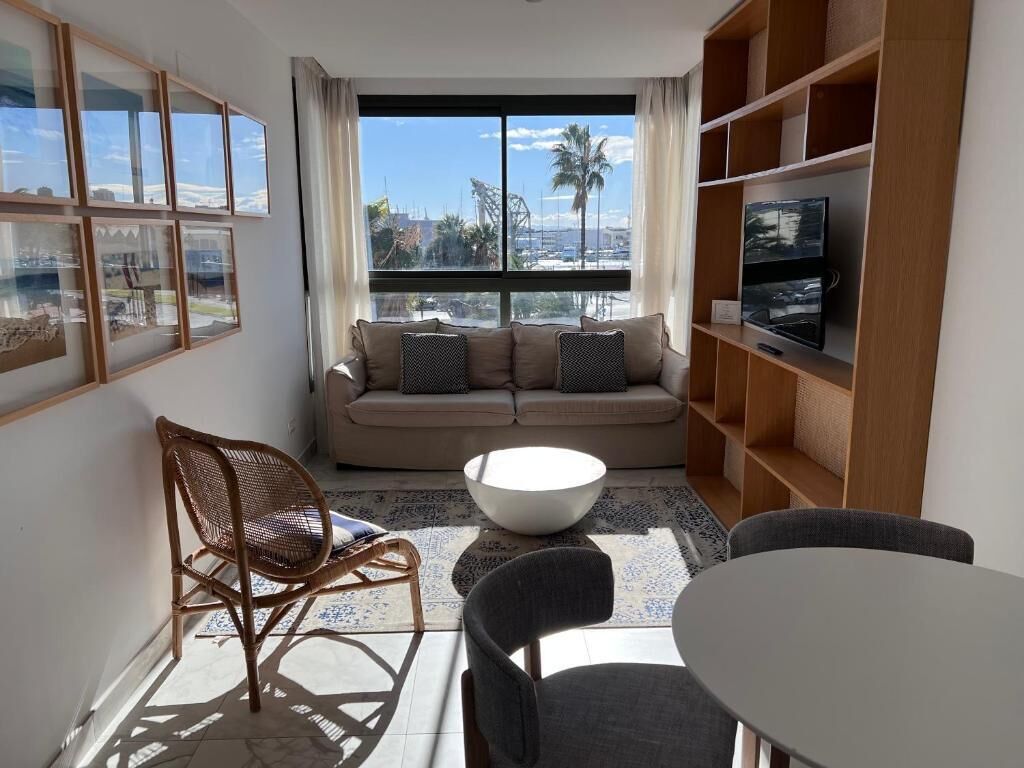 Un salon moderne avec un canapé, des fauteuils, une table basse et un téléviseur posé sur une étagère.