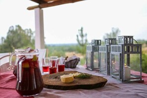 A table with a pitcher of iced tea, glasses, a wooden board with cheese and a sprig of rosemary, and lanterns. - Rabbit House (Azerveira)