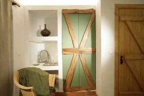 A room with a wooden door, a green-framed mirror, and a wicker chair.