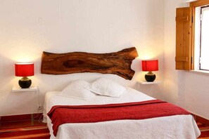 A bedroom with a wooden headboard, two bedside lamps, a bed with white linens, and a red throw blanket. - Rabbit House (Azerveira)