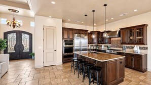 A spacious kitchen with a large island, dark wooden cabinets, stainless steel appliances, and a chandelier. - The Overlook - Triple Primary Luxe, 50 Mile Views (Page)